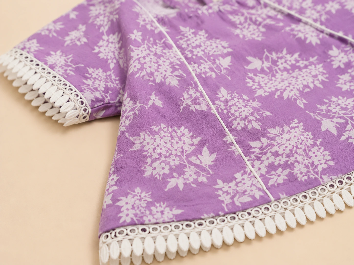 Close-up of white pom-pom lace and lilac floral print