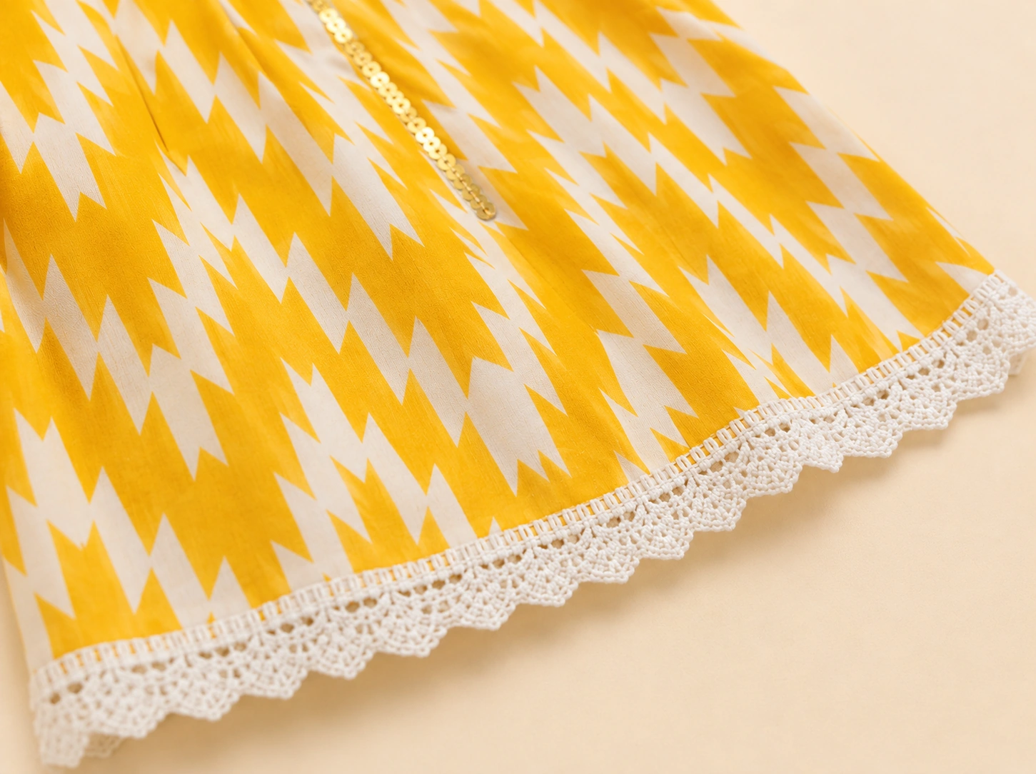 Close-up of gold sequin placket and white lace